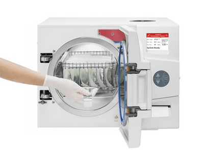 Steam Autoclave, person with gloves inserts packaged tools